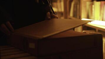 Close-up of mysterious man opening large book. Stock footage. Man opens book in dark library with flashing light. Secret society with mysterious books in night library photo