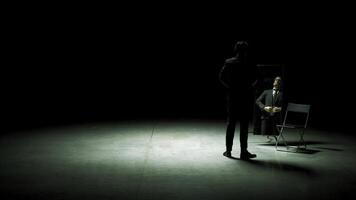 Man in suit in front of mirror. Stock footage. Man on stage with mirror puts on suit. Stage production with one man and mirror on dark stage photo