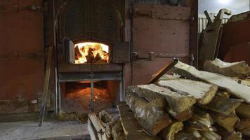 Old stove with firewood in summer. Action. Beautiful oven doors in wall with fire. Outdoor stove with burning wood inside on summer day photo