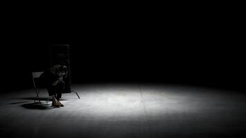 Man in suit cleans his shoes. Stock footage. Theatrical production with one actor in business suit cleaning shoes. Man in suit sits on chair and cleans shoes on stage photo