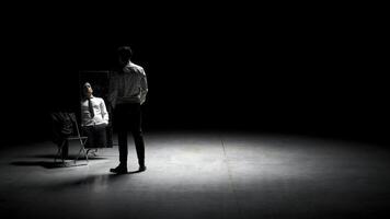 Man in suit in front of mirror. Stock footage. Man on stage with mirror puts on suit. Stage production with one man and mirror on dark stage photo