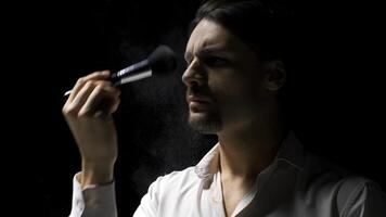 Man applies powder to his face with brush. Stock footage. Man puts powder on face on theater stage. Theatrical production with one man putting powder on face photo