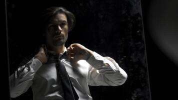 Reflection in mirror of man in suit on black background. Stock footage. Man in suit is preparing for something in front of mirror. Theatrical production with reflection of man in suit in mirror photo