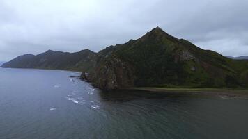 Top view of mountain coast with rocks on cloudy day. Clip. Beautiful landscape of sea and mountain island in cloudy weather. Fascinating landscape of northern coast with sea and rocks photo