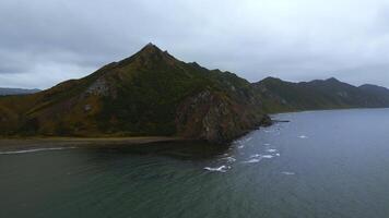 Top view of mountain coast with rocks on cloudy day. Clip. Beautiful landscape of sea and mountain island in cloudy weather. Fascinating landscape of northern coast with sea and rocks photo