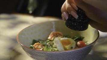 Close-up of woman adding spices to salad. Stock footage. Woman pepper salad with egg. Hearty seasoned salad or bowl with beautiful serving photo