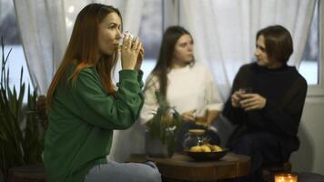 Students talk and relax in cozy cafe. Media. Beautiful young woman is drinking tea on background of talking couple. Students relax and drink tea in college cafe photo