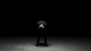 Man in suit stands emotionally on stage. Stock footage. Man in suit stands on stage with dramatic look. Elegant dramatic man on dark stage in emotional production photo