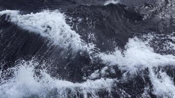 Beautiful waves from moving boat. Clip. Splashes of waves from moving sea boat. Beautiful waves moving sideways from floating boat in sea photo