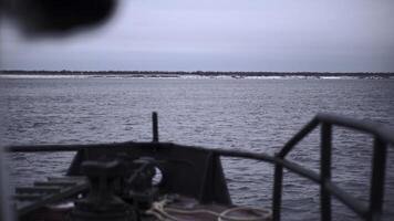 Fishing vessel on background of shore in winter. Clip. Front part of sailing ship to shore in winter. Fishing boat sails to shore on winter day photo