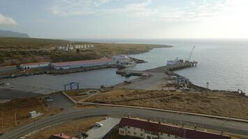 Top view of sea port with sand on north coast. Clip. infrastructure of seaport on seashore. Beautiful landscape of village with seaport on coast of mountain coast photo