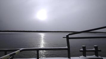 Sea vessel with snow floating on river. Clip. Sailing on sea vessel along river on winter day. Close-up of floating fishing vessel with snow on river near winter shore photo