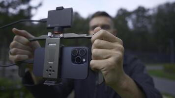UK, London - September 15, 2023. Man professionally shoots on phone with stabilizer. Action. Cinematic shooting on new iPhone 15 pro. Shooting with stabilizer for cinematic effect with new iPhone 15 photo