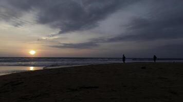 dramático mar amanecer en nublado cielo. acción. ondulado arena mar zapato y un Pareja reunión nuevo día. foto