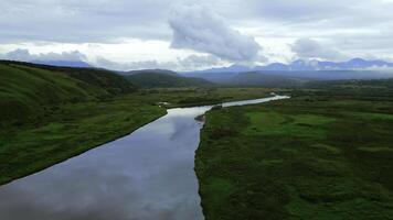 Flying above river and green valley as a backdrop. Clip. Aerial view of summer green meadow and long narrow river. photo