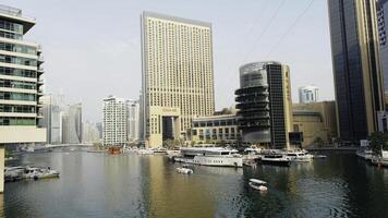 A view of the beautiful city of Dubai and the water canal. Action. Sailing boats and sunny embankment. photo