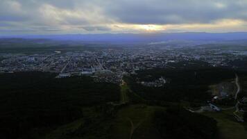 aéreo de el ciudad y grande verde sierras. acortar. verano grande ciudad y nublado cielo durante puesta de sol. foto