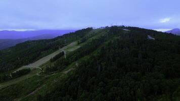 Aerial view of cable cars in mountains. Clip. Travel and outdoor activities, hills, coniferous trees and blue sky. photo