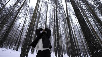 European man standing in wInter forest on a winter day. Media. Blond man raising his hands to warm up. photo
