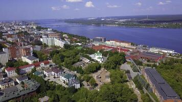 Aerial view of a summer city located along the wide river. Clip. Green park zones and streets under the sun. photo