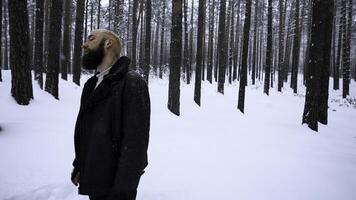 Young man in winter woods looking lost and frustrated. Media. Man in cold clothes in severe winter temperatures trying to survive. photo