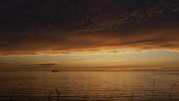 Small boat on lake at sunset. Clip. Breathtaking bright orange sunset above rippling lake. photo