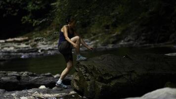 Young caucasian girl walking carefully on stony path and river. Creative. Concept of active lifestyle and hiking. photo