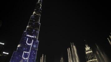 DUBAI - UAE, APRIL 3, 2023. Dancing fountains at Dubai Mall near Burj Khalifa. Action. Beautiful fountain performance at night in popular tourist area. photo