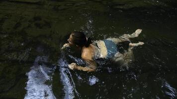 A young boy bathing in a mountain river pool. Creative. Child having fun in a summer natural pond. photo