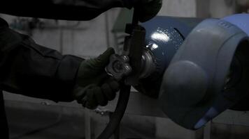 Close up of worker in gloves turning gas cylinder valve. Clip. Industrial background of the factory. photo