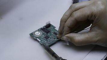 Close up of engineer does computer motherboard soldering. Creative. Painstaking work of soldering a chip. photo