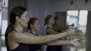 grupo de juguetón personas durante un gimnasio formación con un entrenador. medios de comunicación. muchachas grupo de Atletas balanceo manos antes de comenzando un rutina de ejercicio yoga sesión. foto