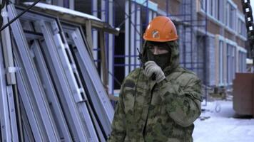 Worker using portable radio and hanging chains of crane on building site. Clip. Construction of the residential buildings, high rise residential complex under construction. photo