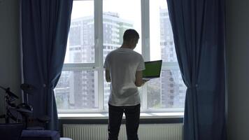 Young man working from home, concept of freelance. Media. Man holding laptop with green chroma key screen and typing. photo