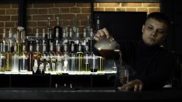 Close up of bartender at a bar counter pouring alcohol into vintage glass. Media. Pouring red hot alcoholic tincture with steam. photo