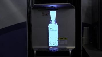 USA - New York, January 7, 2024. Modern water dispenser pouring fresh water into the bottle eco gap. Media. Clean water for healthy life, glowing details of a cooler. photo