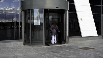 Two female friends entering modern shopping center or office building. Media. Walking through glass rotating door. photo