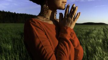 Young pretty girl woman meditating with closed eyes. Stock clip. Praying while standing in a field with a beautiful view on a windy summer day at sunset. photo