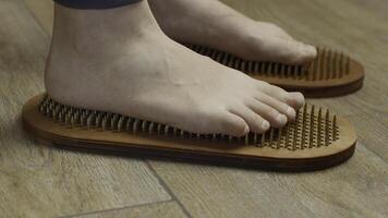 Female feet standing on boards with nails, close up. Media. Barefoot female standing on yoga nails board. photo