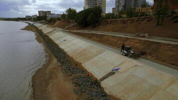 construcción y fortalecimiento de un nuevo la seguridad terraplén a lo largo el río. acortar. aéreo ver ov el mejorando ciudad área. foto