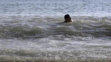 Happy child enjoys swimming in the sea on a hot summer day. Creative. Strong waves and boy in water. photo