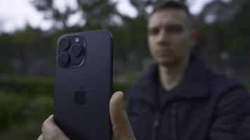 UK, London - September 15, 2023. Man takes pictures on iPhone 15. Action. Close-up of Apple logo on new iPhone 15 pro in hands of man. Man shoots on new iPhone 15 pro with improved shooting quality photo