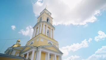 Picturesque view of Orthodox church with a tall yellow and white tower. Clip. Beautiful christian church on background of blue sky in summer. video