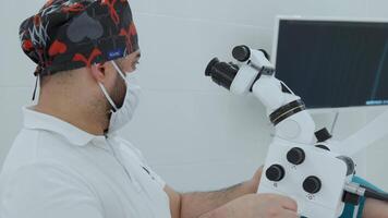 Male doctor using microscope in laboratory. Action. Man in lab examines sample during work in clinic in daytime. video