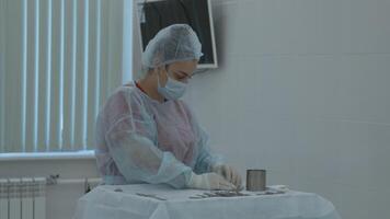 förberedelse för de kirurgi. handling. flera olika kirurgi verktyg på de tabell i rörelse rum, skrubba sjuksköterska i sudd handskar. video