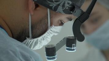 Surgeon head with professional glasses at operating room. Action. Close up side view of a doctor in glasses with binocular magnifiers. video