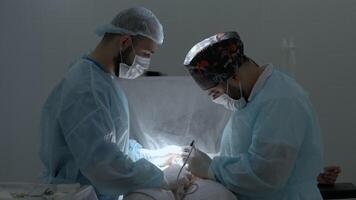 chirurgiens travail dans en fonctionnement pièce à une hôpital. action. deux Masculin médecins à travail. video