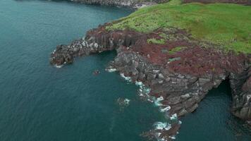 Aerial view of the picturesque cliff and azure sea. Clip. Green grass and stony shore. video