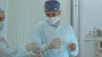 Nurse helping doctor to put on nitrile surgical gloves. Action. Professional medical safety and hygiene for surgery and medical exam, protection against infection. video