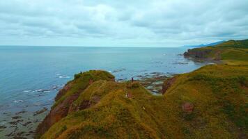 Top view of beautiful seascape with tourists on rock. Clip. Inspiring approach to edge of rocky coast. Beautiful view of tourists on cliff overlooking sea horizon video